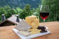 Cheese collection, Swiss cow cheese emmental, tomme and dark chocolate, glass of red wine from Savoie and mountains village in Royalty Free Stock Photo