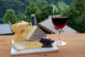 Cheese collection, Swiss cow cheese emmental, tomme and dark chocolate, glass of red wine from Savoie and mountains village in Royalty Free Stock Photo