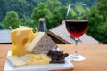 Cheese collection, Swiss cow cheese emmental, tomme and dark chocolate, glass of red wine from Savoie and mountains village in Royalty Free Stock Photo