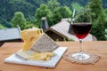 Cheese collection, Swiss cow cheese emmental, tomme and dark chocolate, glass of red wine from Savoie and mountains village in Royalty Free Stock Photo