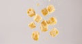 Cheese cube pieces falling with droplets against gradient gray background Royalty Free Stock Photo