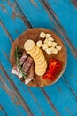 Cheese cubes, capsicum, meat, rosemary and biscuits on wooden board