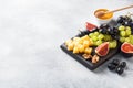 Cheese cubes, fresh fruit figs grapes Honey walnut on wooden chopping Board. Copy space Royalty Free Stock Photo