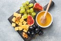 Cheese cubes, fresh fruit figs grapes Honey walnut on wooden chopping Board. Copy space Royalty Free Stock Photo