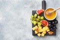 Cheese cubes, fresh fruit figs grapes Honey walnut on wooden chopping Board. Copy space Royalty Free Stock Photo