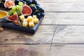 Cheese cubes, fresh fruit figs grapes Honey walnut on wooden chopping Board. Copy space Royalty Free Stock Photo