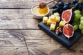 Cheese cubes, fresh fruit figs grapes Honey walnut on wooden chopping Board. Copy space Royalty Free Stock Photo