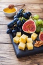 Cheese cubes, fresh fruit figs grapes Honey walnut on wooden chopping Board. Copy space Royalty Free Stock Photo