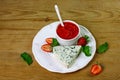 Cheese dourble or brie with blue mold with strawberry jam and mint on a white plate, wooden background. Food for wine and romantic