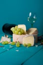 Cheese, grapes and wine on wooden cyan surface.