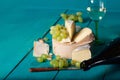 Cheese, grapes and wine on wooden cyan surface.