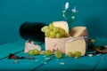 Cheese, grapes and wine on wooden cyan surface.