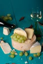 Cheese, grapes and wine on wooden cyan surface.
