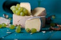 Cheese, grapes and wine on wooden cyan surface.