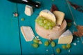 Cheese, grapes and wine on wooden cyan surface.