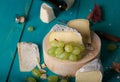 Cheese, grapes and wine on wooden cyan surface.