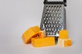 Cheese grater and blocks of cheddar cheese on solid background Royalty Free Stock Photo