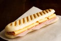 Cheese and ham toasted panini. On brown paper and wood.