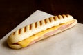 Cheese and ham toasted panini. On brown paper and wood.