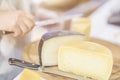 Cheese heads on market counter, seller sells cheese, cut cheese heads on wooden market board. Selective focus Royalty Free Stock Photo