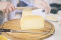 Cheese heads on market counter, seller sells cheese, cut cheese heads on wooden market board. Selective focus Royalty Free Stock Photo