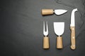 Cheese knives and fork on black stone table, flat lay