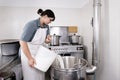 Cheese Maker pours milk into a steel container