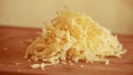 cheese mastery: shredded yellow cheese on wooden board closeup