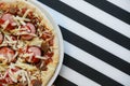 Close up of freshly home made pizza on a white plate with cheese, meat, onions, spicy products. Italian traditional food