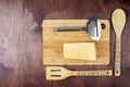 Cheese and a metal grater on a cutting Board and bamboo spatulas on a mahogany wood background