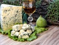 Cheese with mold on a green lettuce leaf with figs on a wooden background. Golden shot glass with alcohol Royalty Free Stock Photo