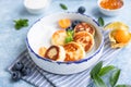 Cheese pancakes, fritters or syrniki with blueberry, physalis and yogurt, blue background. Healthy and tasty breakfast