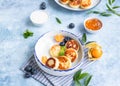 Cheese pancakes, fritters or syrniki with blueberry, physalis and yogurt, blue background. Healthy and tasty breakfast