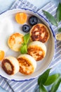 Cheese pancakes, fritters or syrniki with blueberry, physalis and yogurt, blue background. Healthy and tasty breakfast