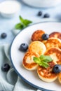 Cheese pancakes, fritters or syrniki with blueberry, physalis and yogurt, blue background. Healthy and tasty breakfast