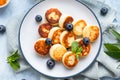 Cheese pancakes, fritters or syrniki with blueberry, physalis and yogurt, blue background. Healthy and tasty breakfast