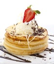 Cheese pancakes with vanilla ice and chocolate sprinkles decorated with whip cream and strawberry fruit, arranged on a plate