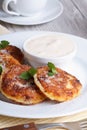 Cheese pancakes on a white plate with sour cream vertical