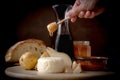 Cheese, pears, wine, and bred on the board with a hand pouring honey with honey spoon from a jar Royalty Free Stock Photo