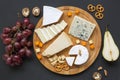 Cheese plate. Assorted cheeses on round wooden board with fruits, walnuts and pretzels. Royalty Free Stock Photo