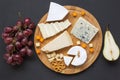 Cheese plate. Assorted cheeses on round wooden board with fruits, walnuts and pretzels. Food for wine.