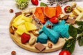 Cheese plate. Assorted multicolored hard Dutch cheeses. Blue and red pesto, aged gouda