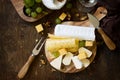 Cheese plate. Assortment of cheeses, grapes and nuts on dark rustic wooden table. Top view flat lay background. Royalty Free Stock Photo