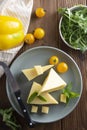 Cheese plate with delicous cheese slices and a cheese knife, wooden table. Top view