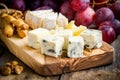 Cheese plate: Emmental, Camembert, Parmesan, blue cheese closeup, with bread sticks and grapes