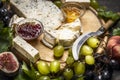 Cheese plate with Gorgonzola and Camembert cheese knife honey jam light and dark grapes a wooden cutting board close up Royalty Free Stock Photo