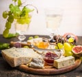 Cheese plate with Gorgonzola and Camembert with honey and jam dark and bright grapes glass of wine grapes on a branch inside on da Royalty Free Stock Photo