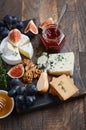 Cheese plate with grapes, figs, crackers, honey, plum jelly, thyme and nuts.