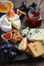 Cheese plate with grapes, figs, crackers, honey, plum jelly, thyme and nuts.