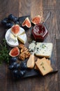 Cheese plate with grapes, figs, crackers, honey, plum jelly, thyme and nuts.